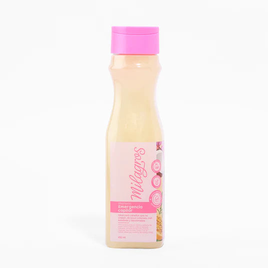 A plastic bottle with a pink cap and label contains Shampoo Emergencia Capilar. The label displays images of fruit such as pineapple and features red text on a white background.